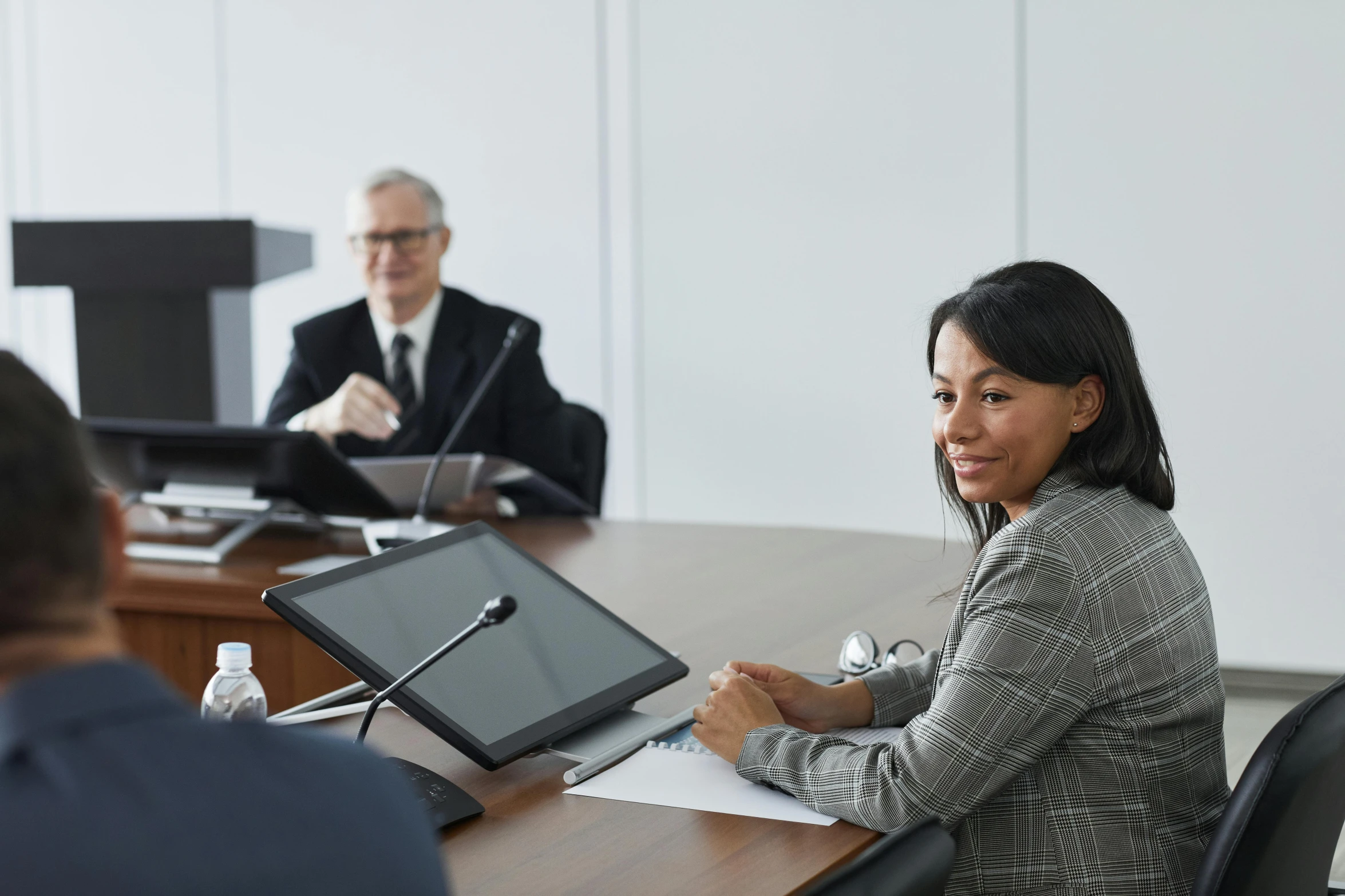 a woman sitting in front of a man in a suit on a laptop computer