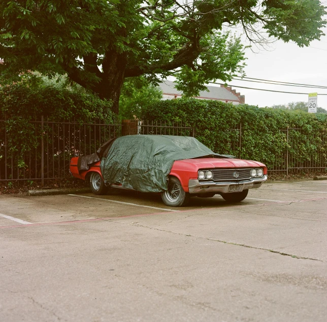 the parked red truck is covered with a black sheet