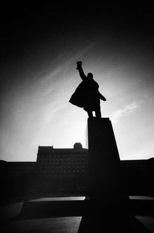 silhouette of man standing on top of structure holding a cell phone