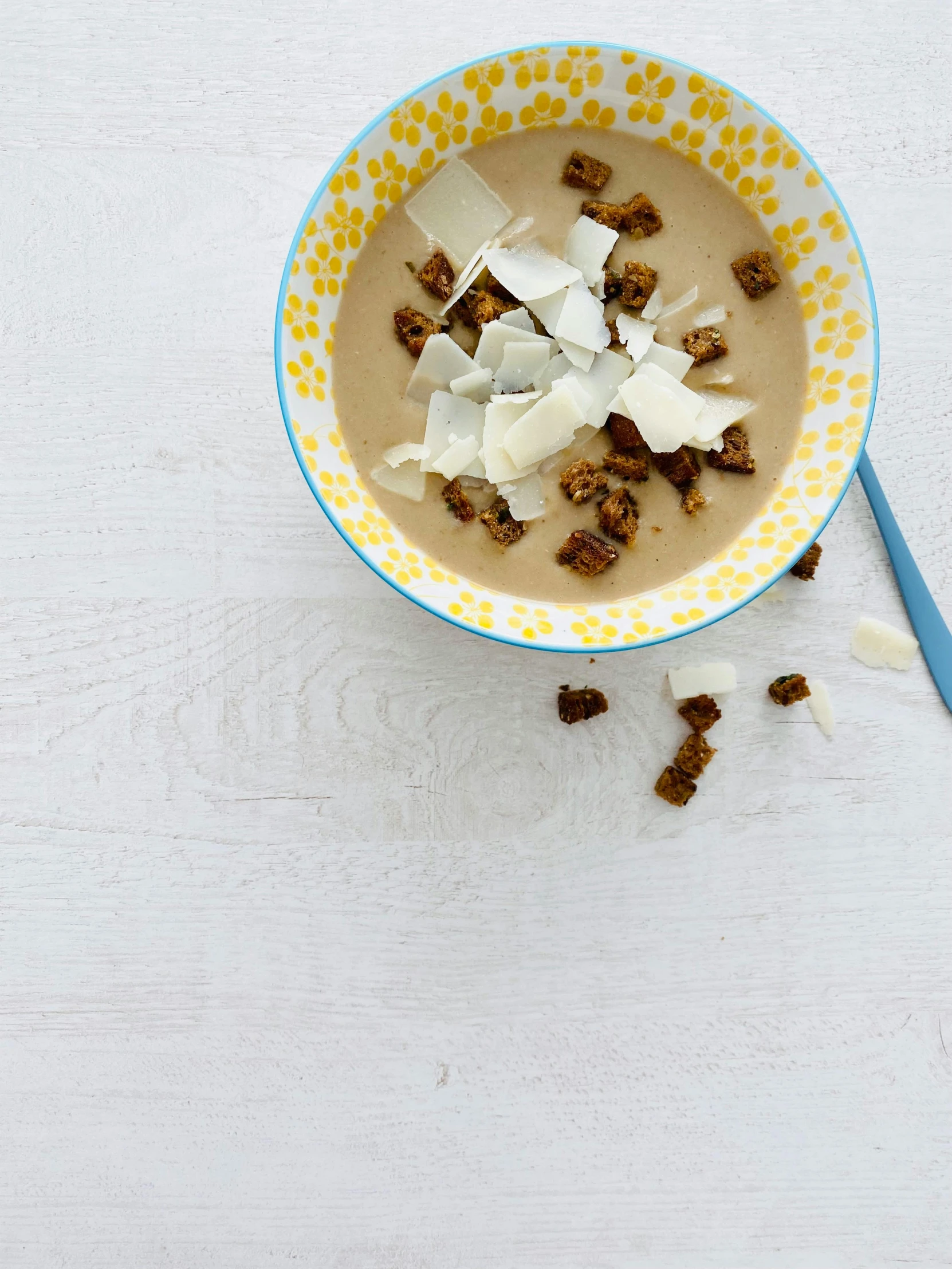 a bowl filled with nuts next to a spoon on a white table