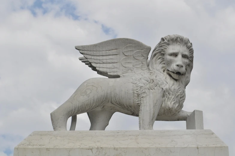 a statue of a winged lion standing above a brick structure