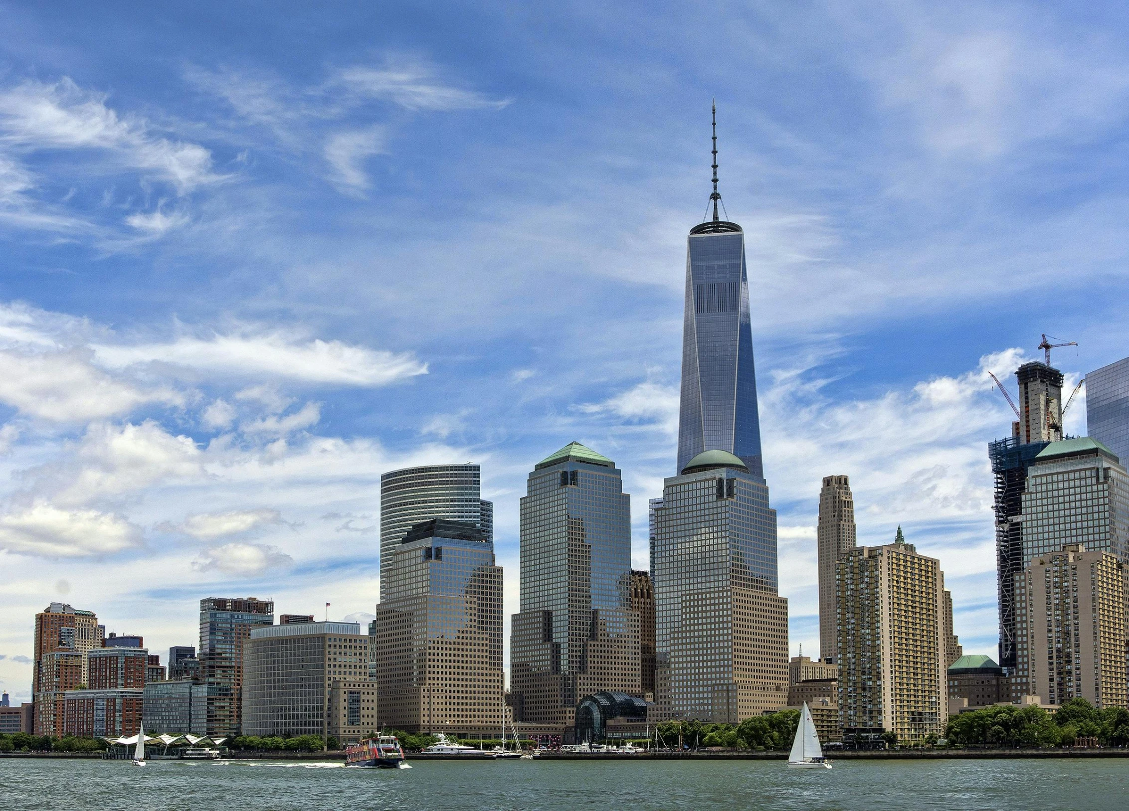 a group of boats floating in a harbor near tall buildings