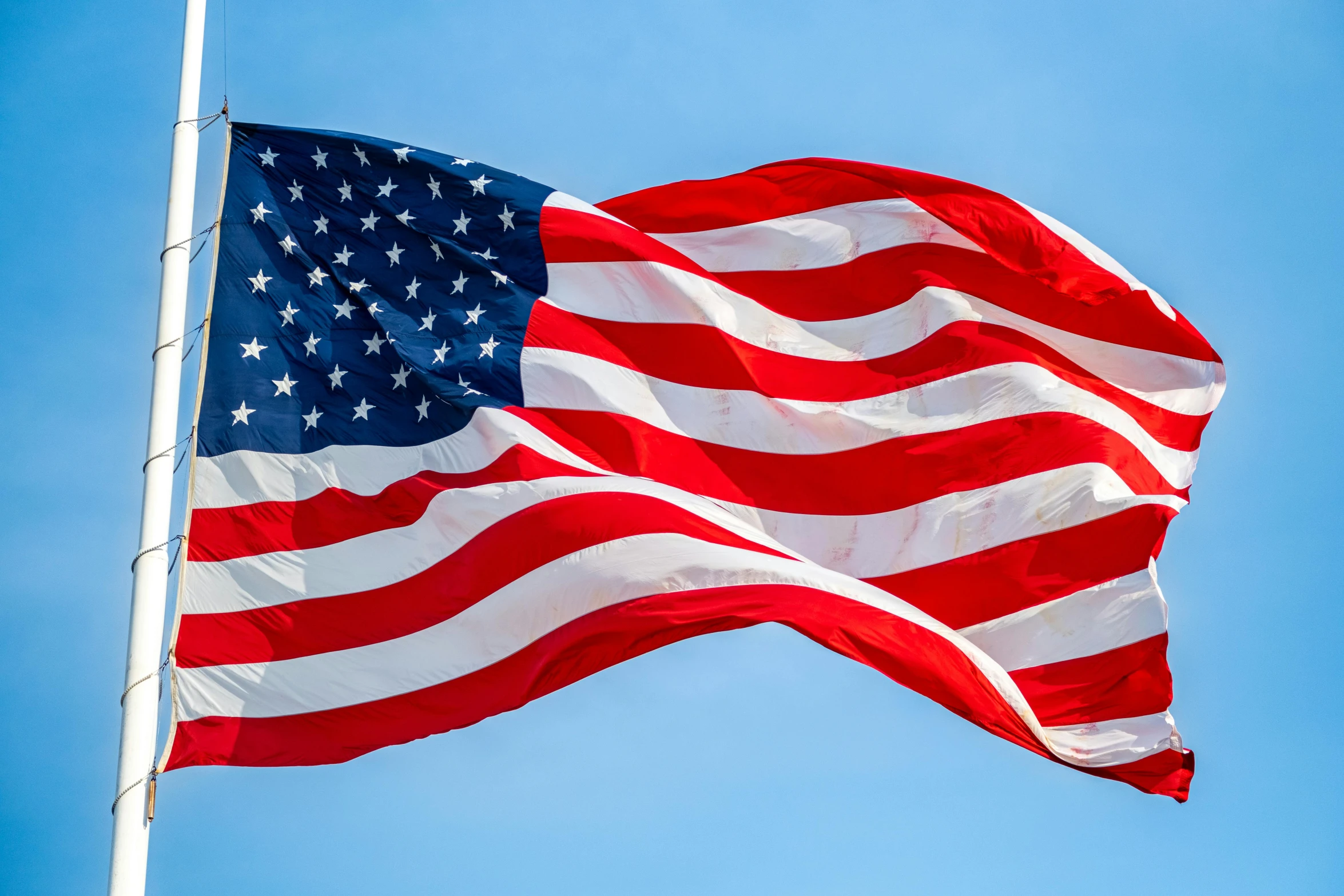 an american flag flies in the blue sky