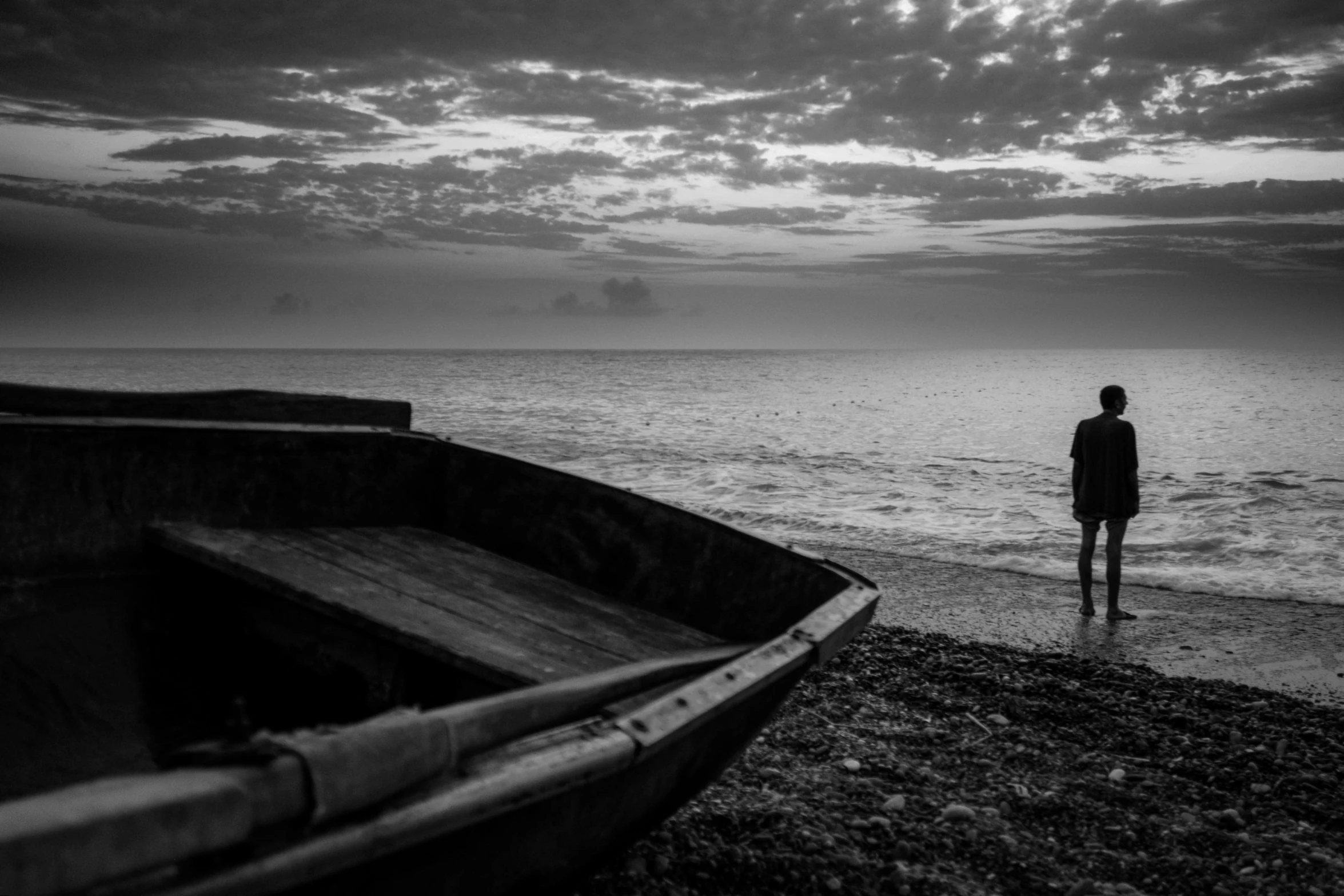 a person standing by some water and boat on the shore