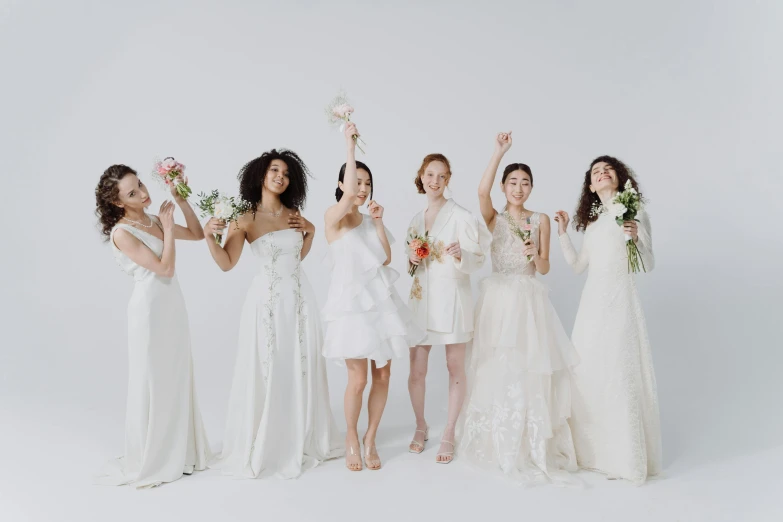 a group of women in dresses are holding bouquets