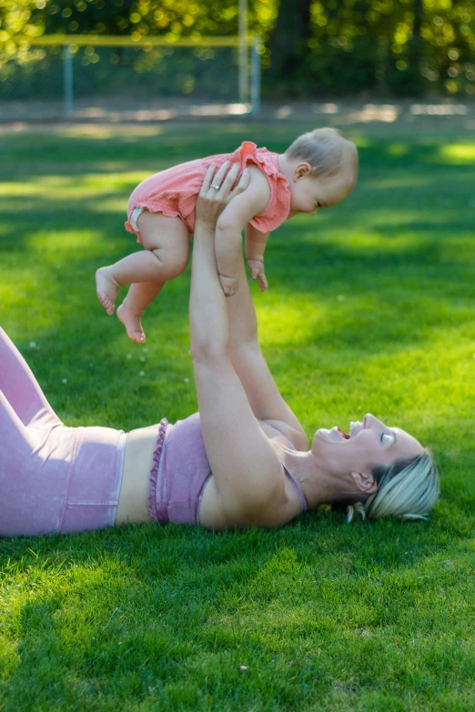 a woman in pink holds her baby up in the air