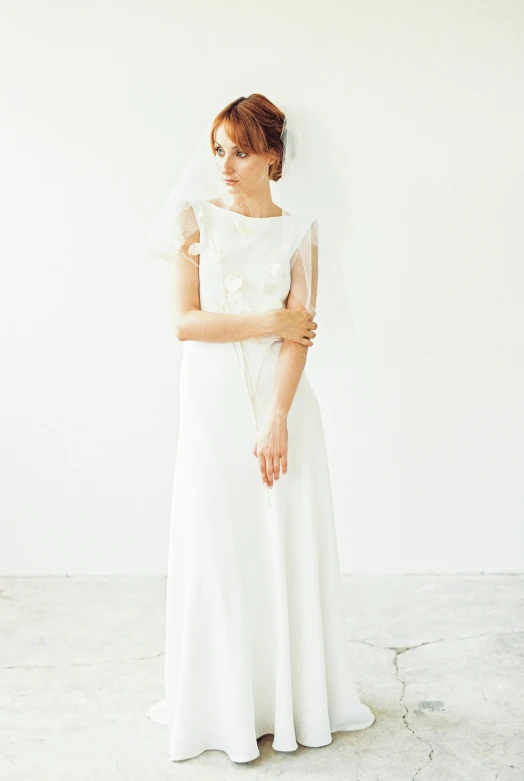 bride in white wedding dress leaning against the wall