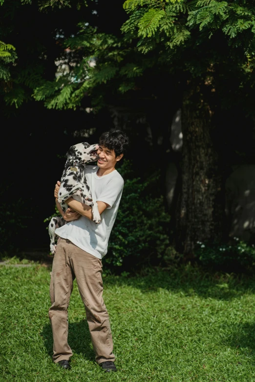 young man holding up an animal standing in a grassy field