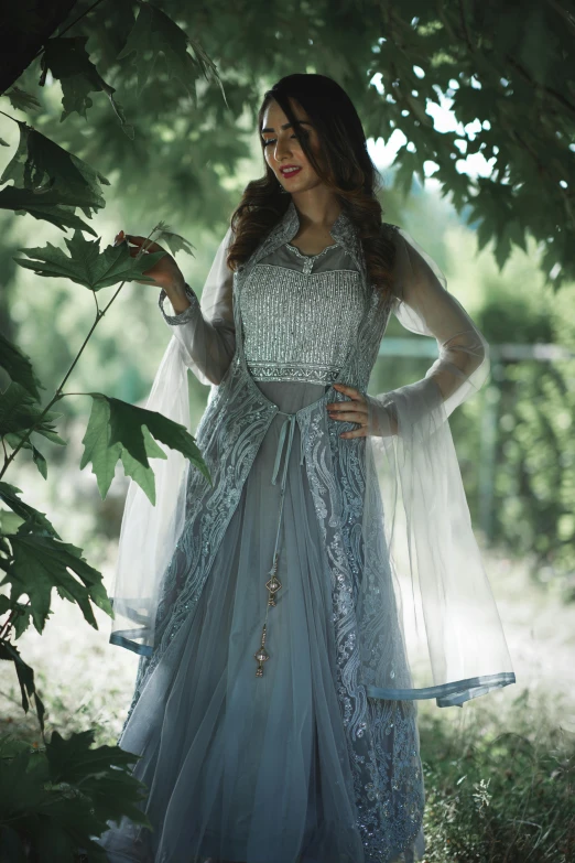 a woman in a blue dress standing under a tree