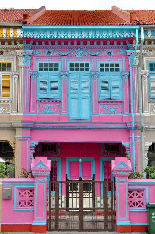 a large blue and pink building with a fence