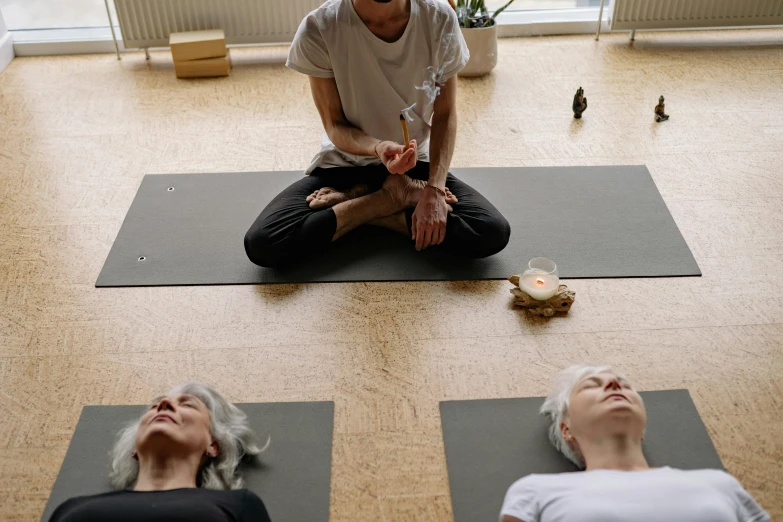 the man is doing yoga on his hands with three other women around him