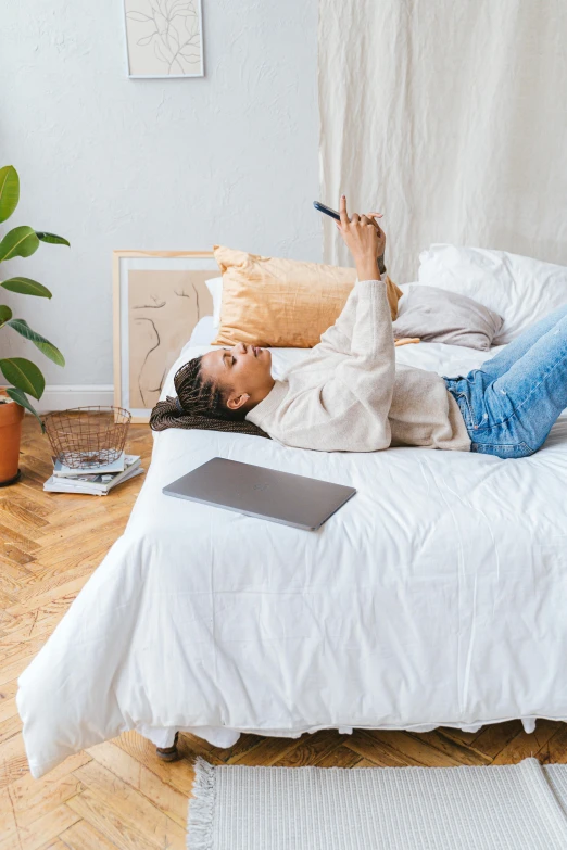 a woman laying on a bed with her laptop on it