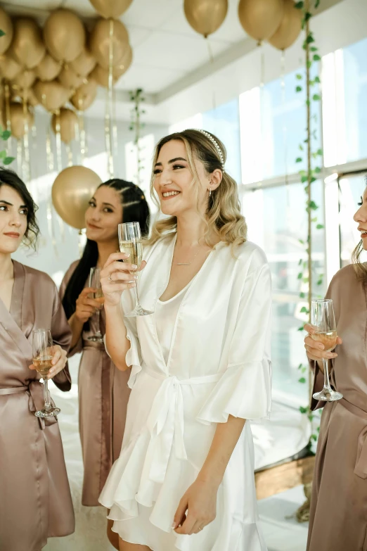 four women in bath robes smile as they hold wine glasses