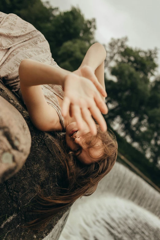 a woman with long hair sitting on a rock