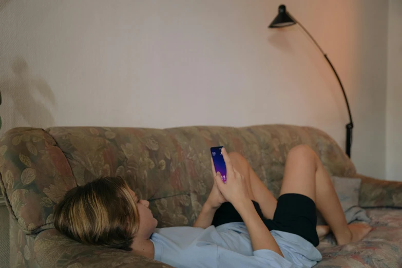 a woman laying down on her stomach watching her phone