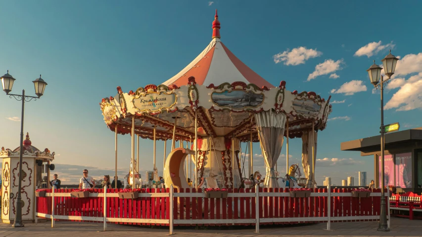 a carousel sitting by the sidewalk under some clouds