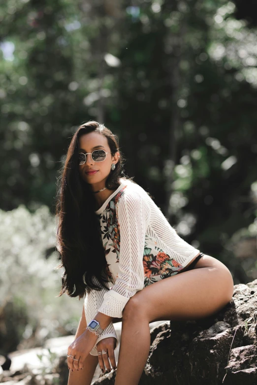 a beautiful woman sitting on a rock in a white top