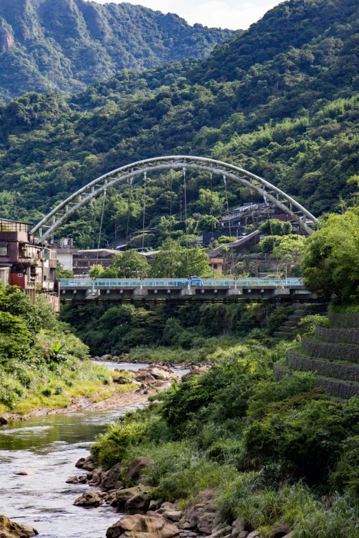 the river runs under the bridge with cars passing underneath