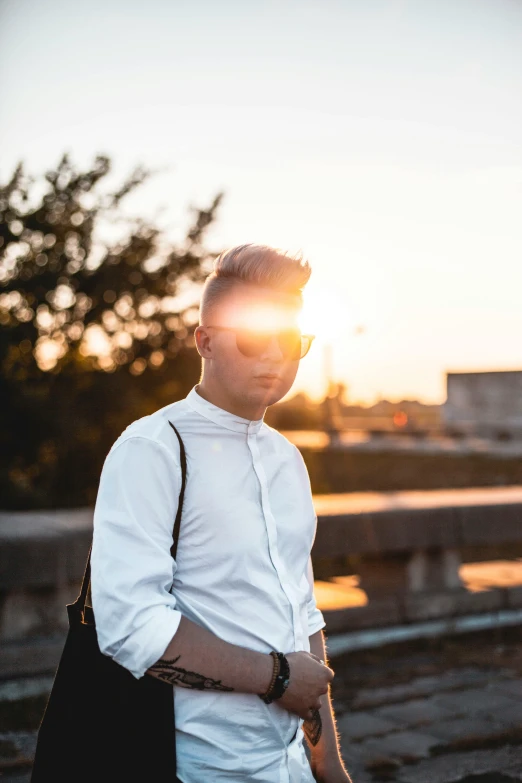 man standing by rail at sunset looking down on him