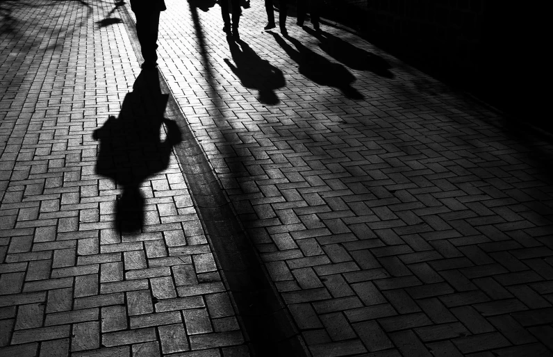 silhouette of people walking in the shadows on a sidewalk