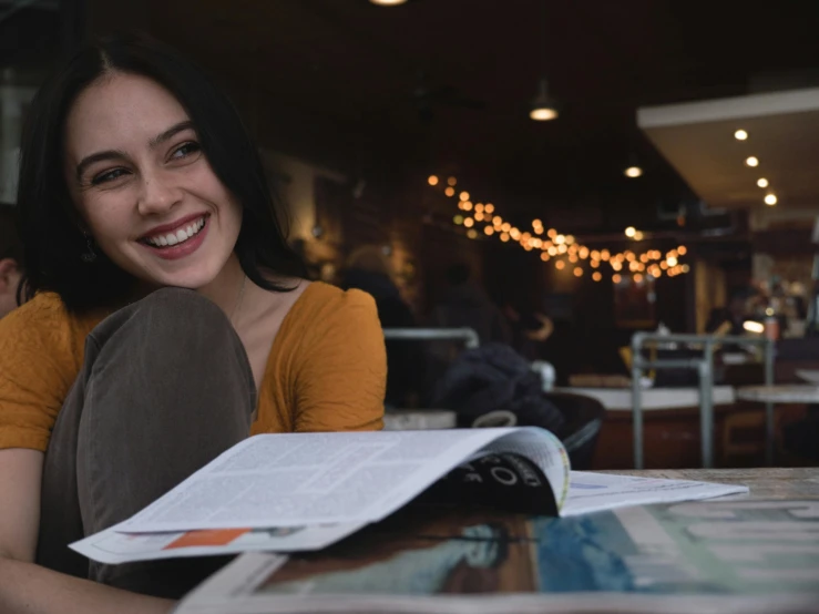 a woman sits in a restaurant and looks back at the camera