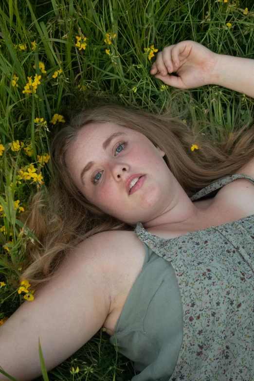 a young woman lies in the grass on her back