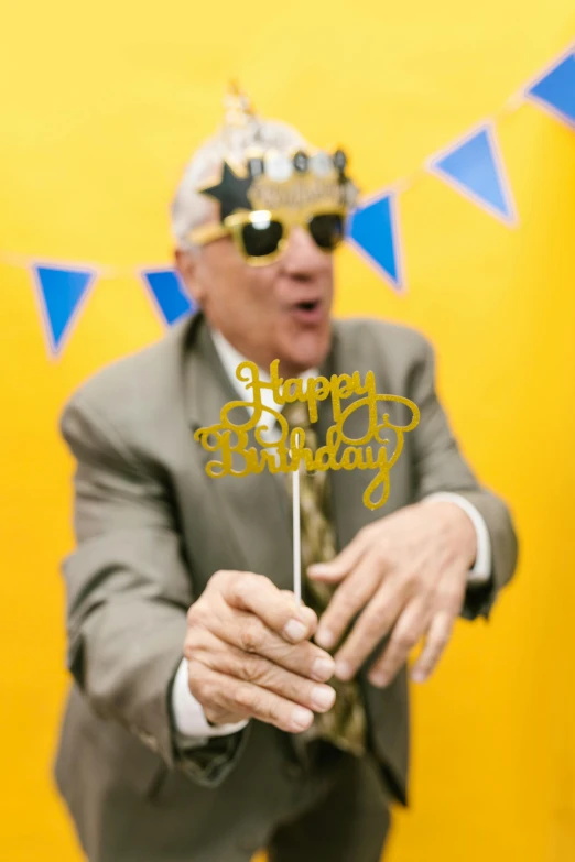 a man in a suit and glasses is holding up a cake