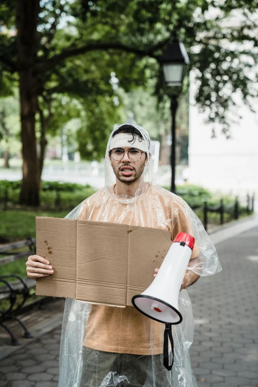 a man standing outside holding up a cardboard board and a large white and red megaphone