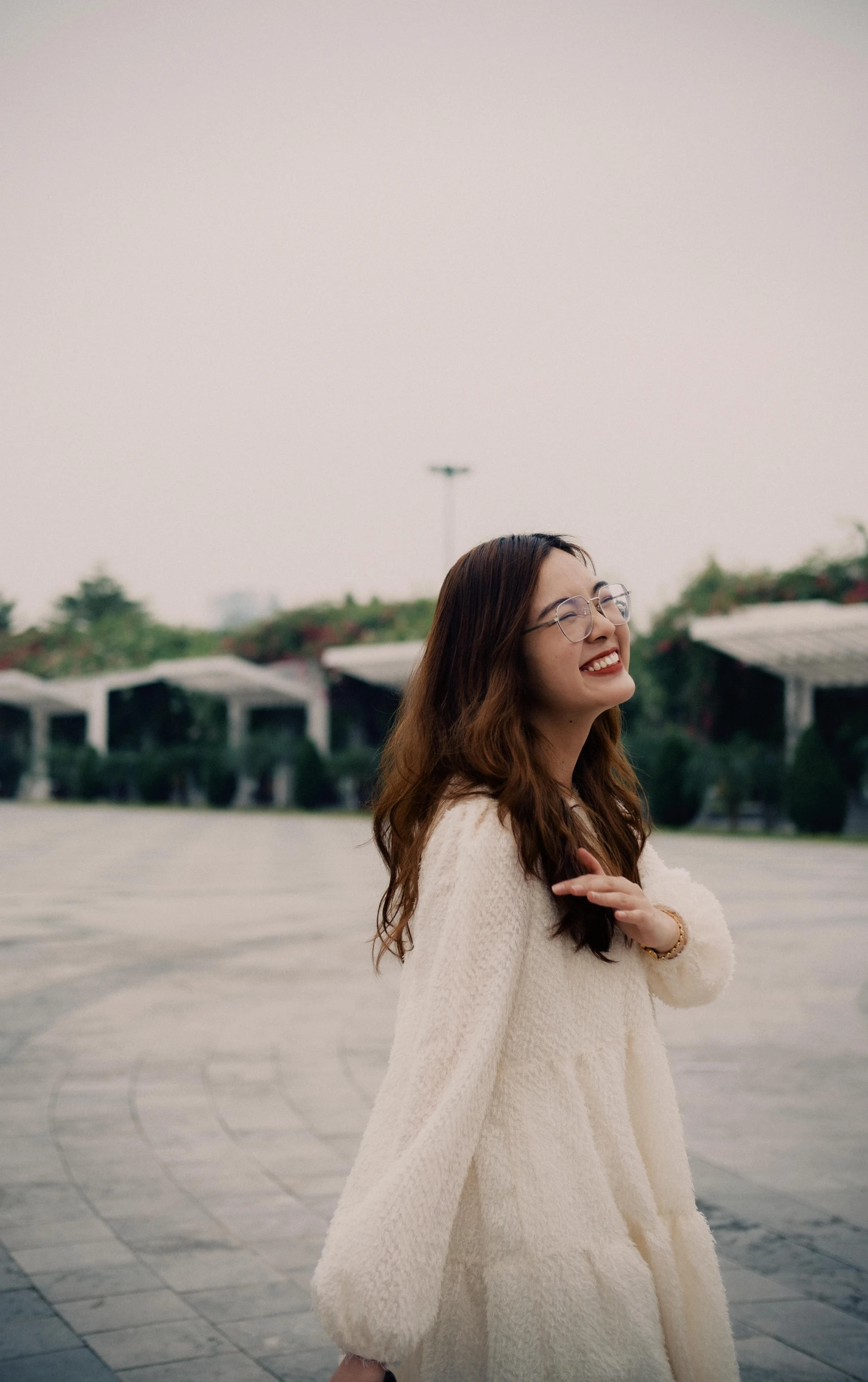 a woman is laughing outside wearing glasses