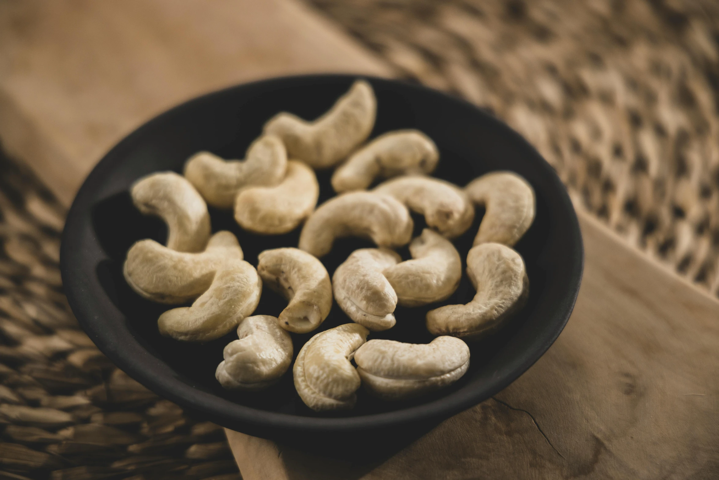 a bowl of cashews on top of a woven cloth