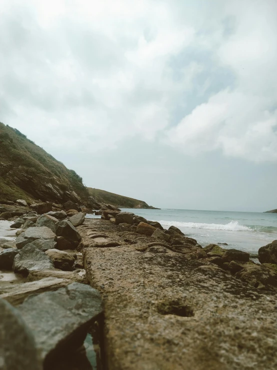 the rocky shore has a large cliff in the distance