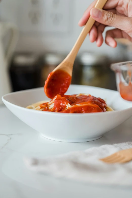 a person is scooping sauce from a bowl into a bowl