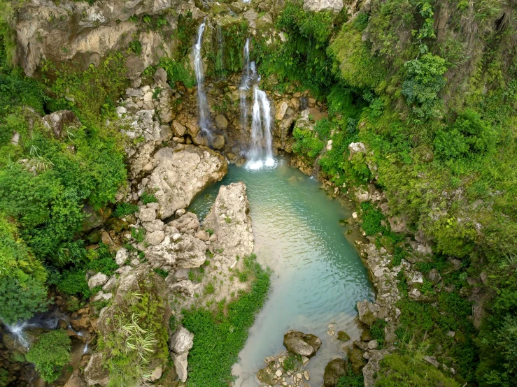 a river running under two waterfalls next to green trees