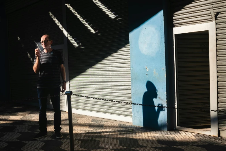 a man standing next to a blue building holding a camera