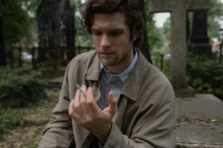 a man with his hands crossed holding a cigarette