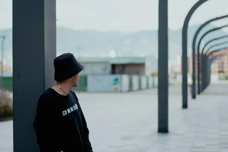 a man wearing a black hat standing next to poles