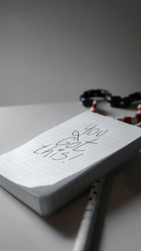 a notepad is laying on a white desk with two keys and the words love note