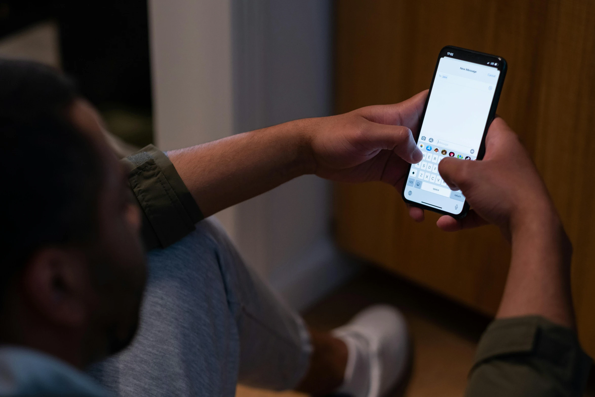 a man in a gray shirt holding a cell phone