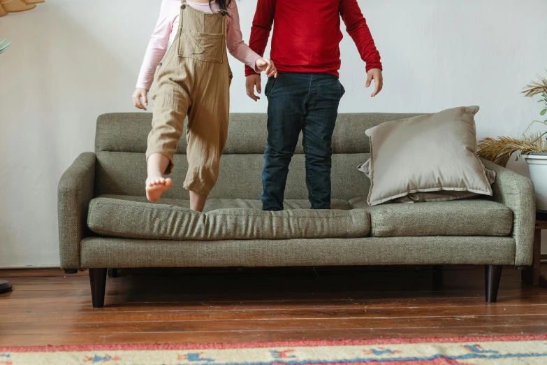 two s jumping on a couch with a cushion