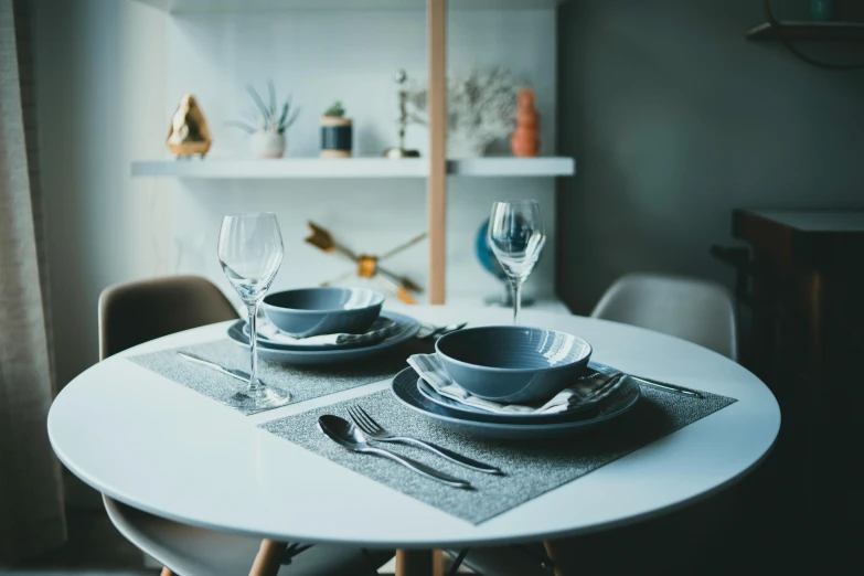 a dining room table with plates and glasses and place settings on it