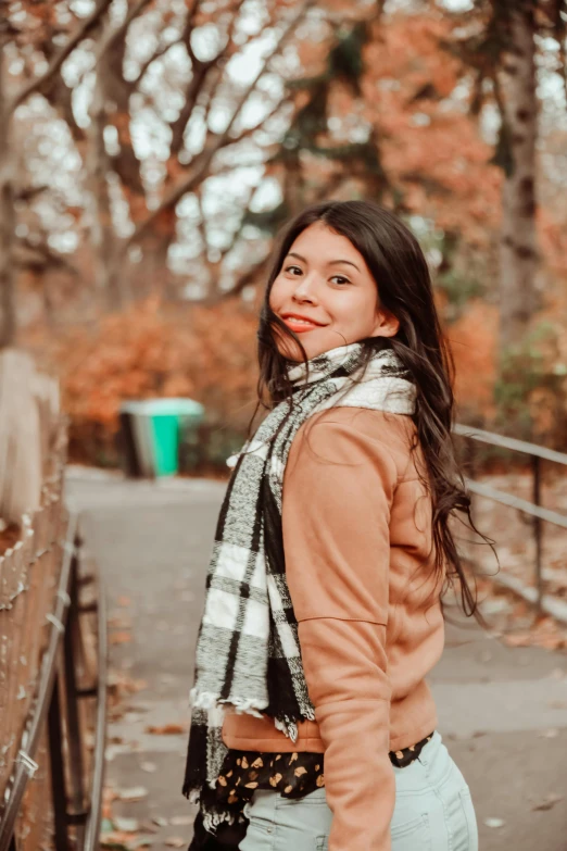 a girl wearing a scarf in front of trees