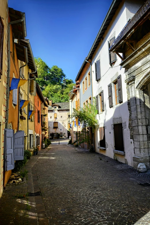 a narrow street with old stone buildings and flags