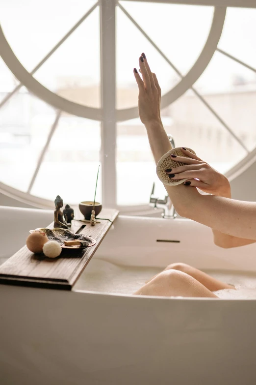 a lady that is laying in a bath tub with her hands up