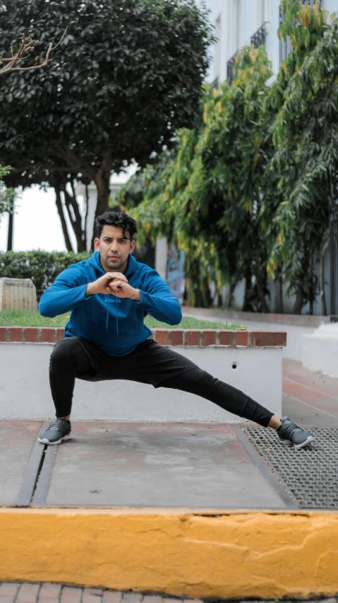 a man poses on the ground in front of some buildings