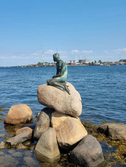 a statue sitting on top of a pile of rocks near the ocean