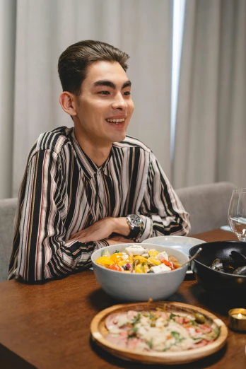 man sitting at a dining table with an asian style dish of sushi