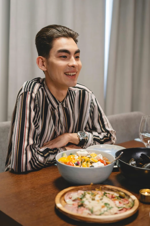 man sitting at a dining table with an asian style dish of sushi