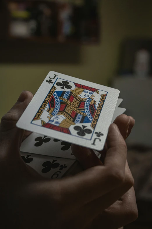 two hands holding playing cards in a dark room