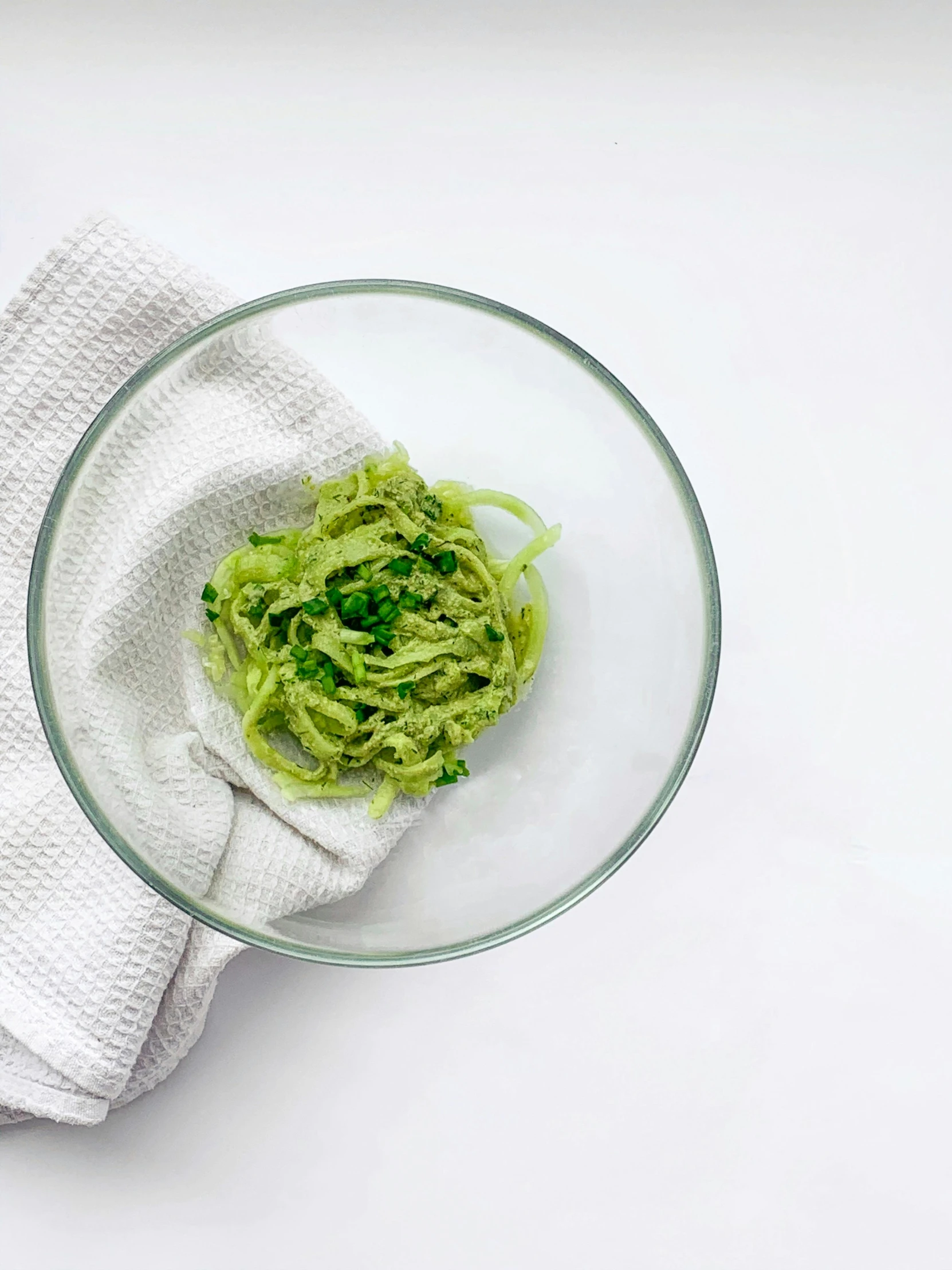 a bowl of pesto and a towel on a table