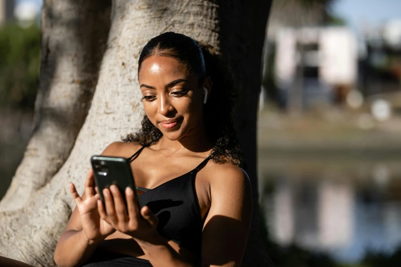 a woman holding a phone under a tree